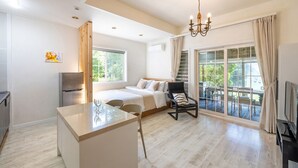 Habitación de hotel moderna con cama, zona de comedor, televisor y balcón con vistas.