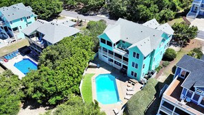Ein großes, zweistöckiges Gebäude mit Swimmingpool, mehreren Balkonen und einem gepflegten Rasen.