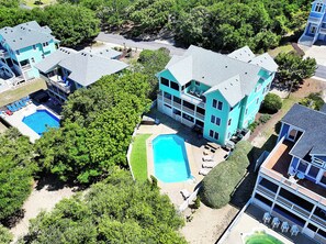 Ein großes, zweistöckiges Gebäude mit Swimmingpool, mehreren Balkonen und einem gepflegten Rasen.