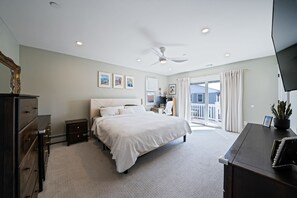 A bedroom with a bed, dresser, nightstand, ceiling fan, and a large window with curtains. - 4 Bedroom House Minutes from the beach! (Long Beach)