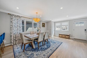 A dining area with a table, chairs, a chandelier, and a patterned rug. - 4 Bedroom House Minutes from the beach! (Long Beach)