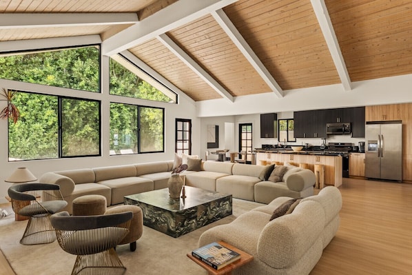 A spacious living area with a large sofa, a coffee table, and a view of the kitchen.