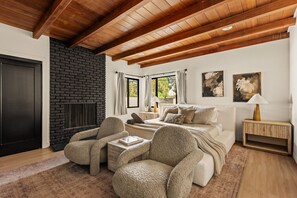 A cozy bedroom with a fireplace, a bed, a sofa, and a nightstand.