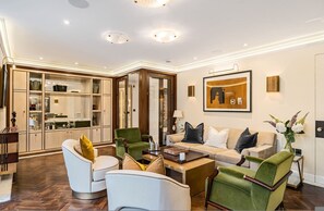 Een ruime woonkamer met een bank, stoelen, een salontafel, en een keuken met kasten en een eettafel.