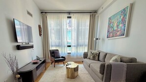 A living room with a sofa, a coffee table, a TV, and a painting on the wall.