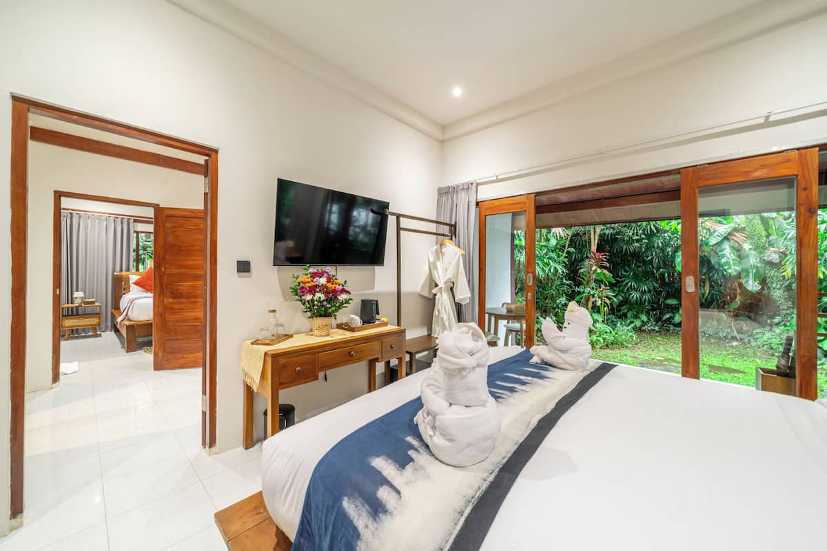 Habitación de hotel con cama, escritorio, televisor y vistas a zonas verdes.