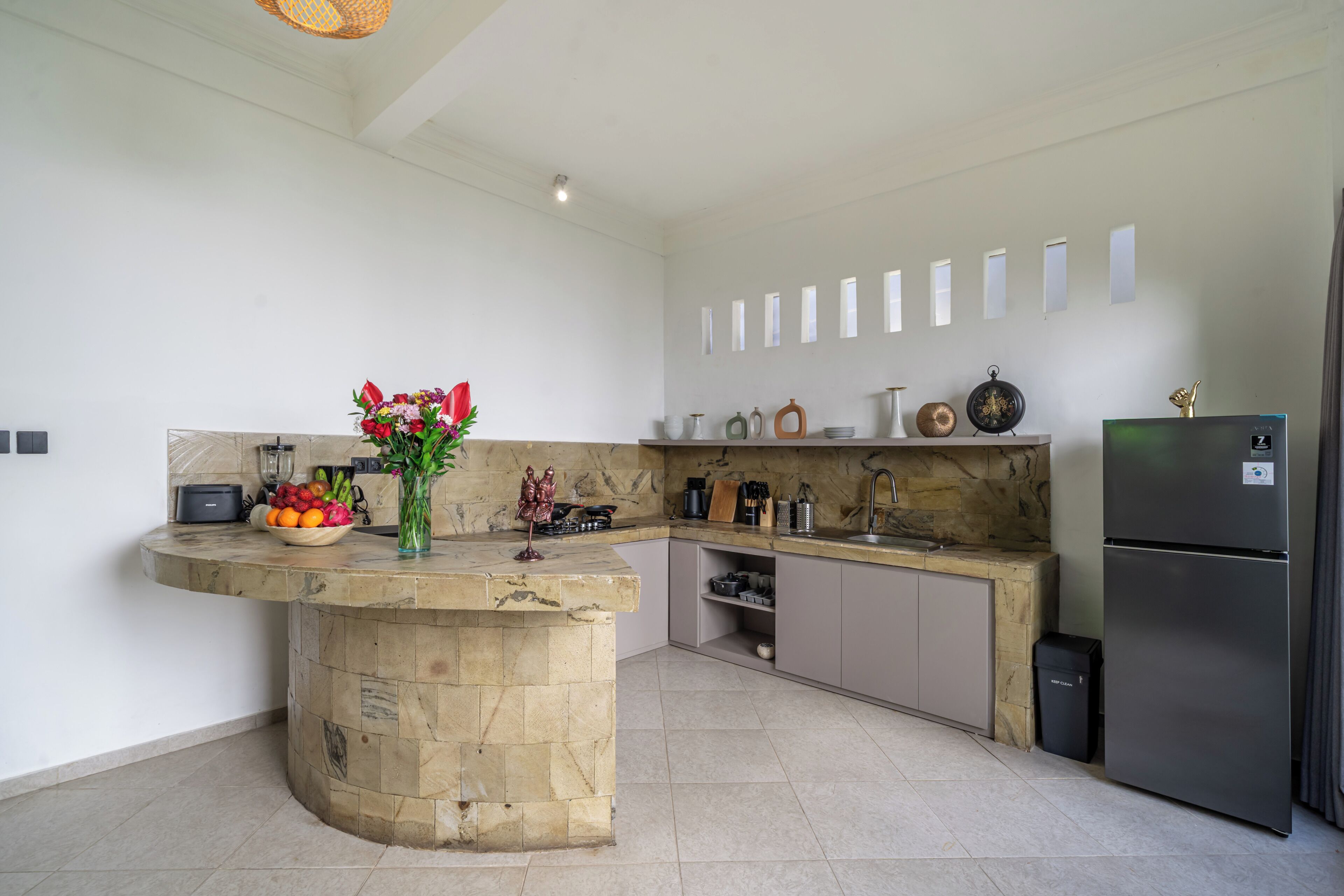 A modern kitchen with a stone island, stainless steel appliances, and a variety of kitchenware.