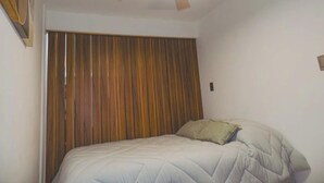 Ein Schlafzimmer mit einem Bett, Deckenventilator und einem Holz-Kopfteil.