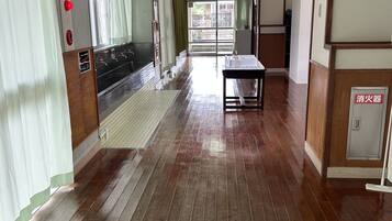 A hallway with wooden flooring, a table, and a window with curtains.