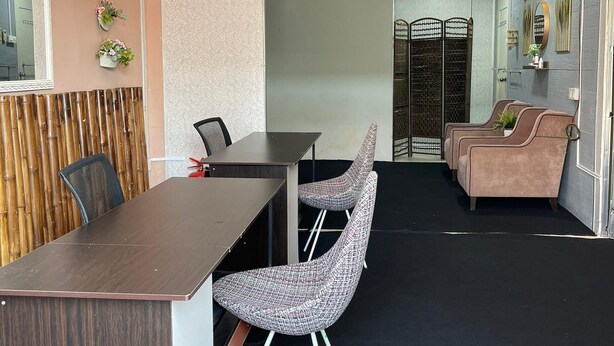 A conference room with a wooden table and chairs, a reception area with a sofa and chairs, and a decorative wall with a sign. - Hotel O D'noor (Kota Bharu)