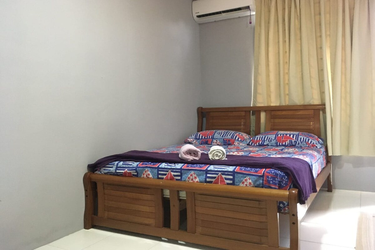 A single bed with a wooden frame, a patterned bedspread, and a pillow.