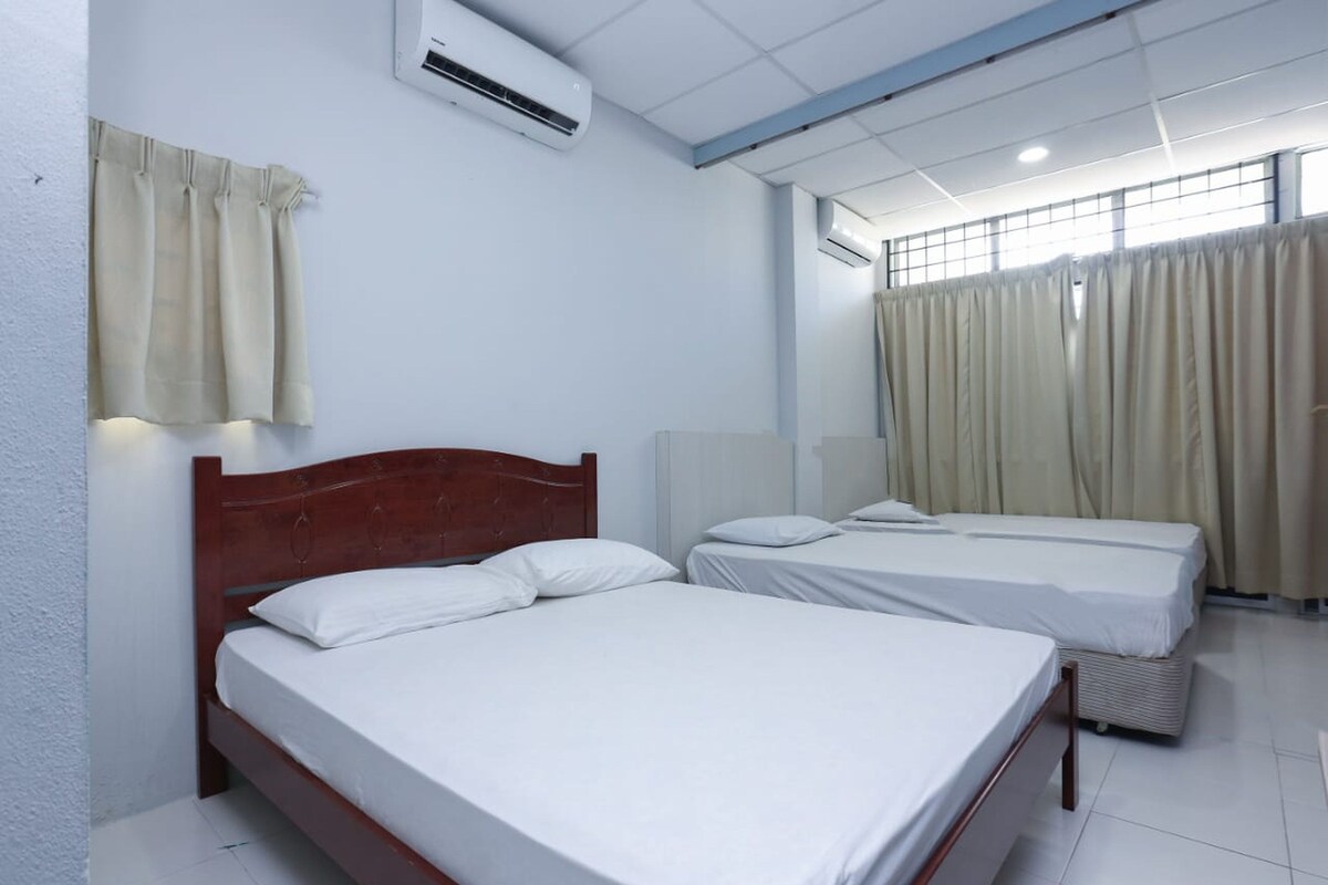 A hotel room with two beds, an air conditioning unit, and curtains.