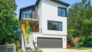 Ein modernes, zweistöckiges Haus mit Balkon, Garage und gepflegtem Rasen.