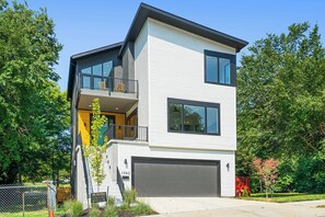 A modern two-story house with a balcony, a garage, and a well-maintained lawn. - 5 Bdr/5ba Luxury new build near downtown and walkable to bars and restaurants (Kansas City)