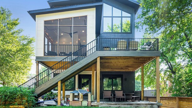 Ein modernes, zweistöckiges Haus mit Balkon, Treppe und Terrassenbereich.