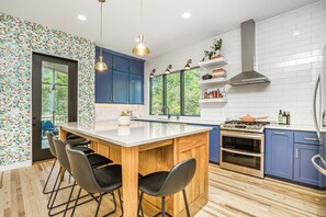 A modern kitchen with a central island, blue cabinets, and a white backsplash. - 5 Bdr/5ba Luxury new build near downtown and walkable to bars and restaurants (Kansas City)