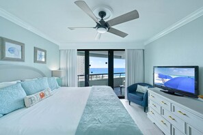 Una habitación de hotel con cama, televisión, balcón y vistas, además de un ventilador de techo.