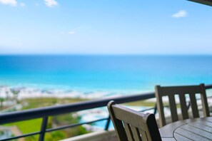 Una mesa y una silla de madera en un balcón con vista al mar.