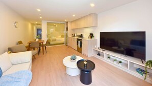 Una sala de estar moderna con un sofá, una mesa de centro, televisor y zona de cocina.