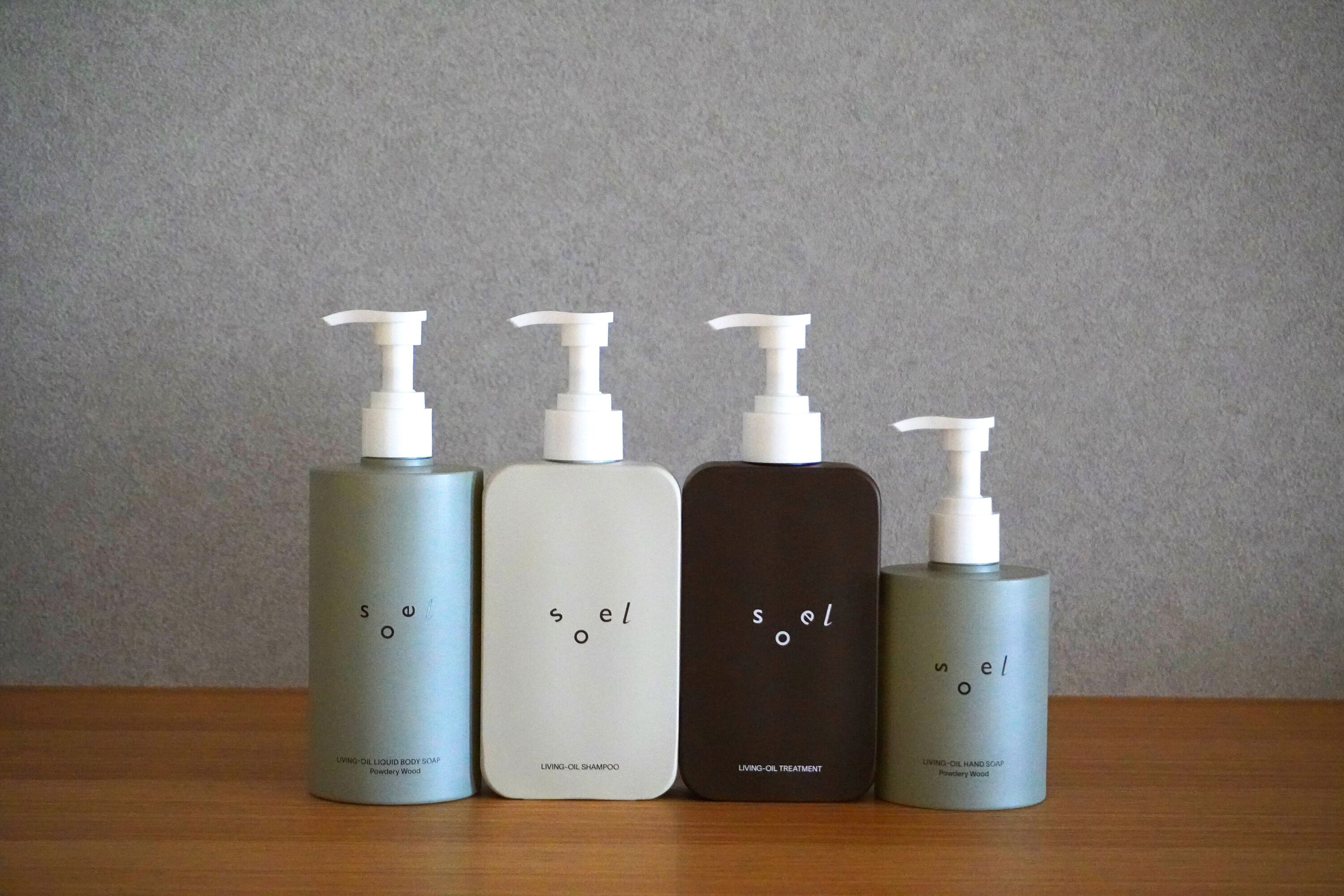 Four bottles of 'soel' brand body care products on a wooden surface.