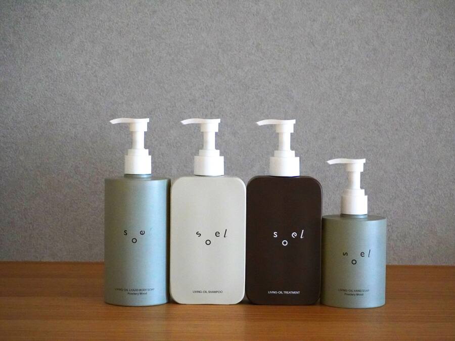 Four bottles of 'soel' brand body care products on a wooden surface.
