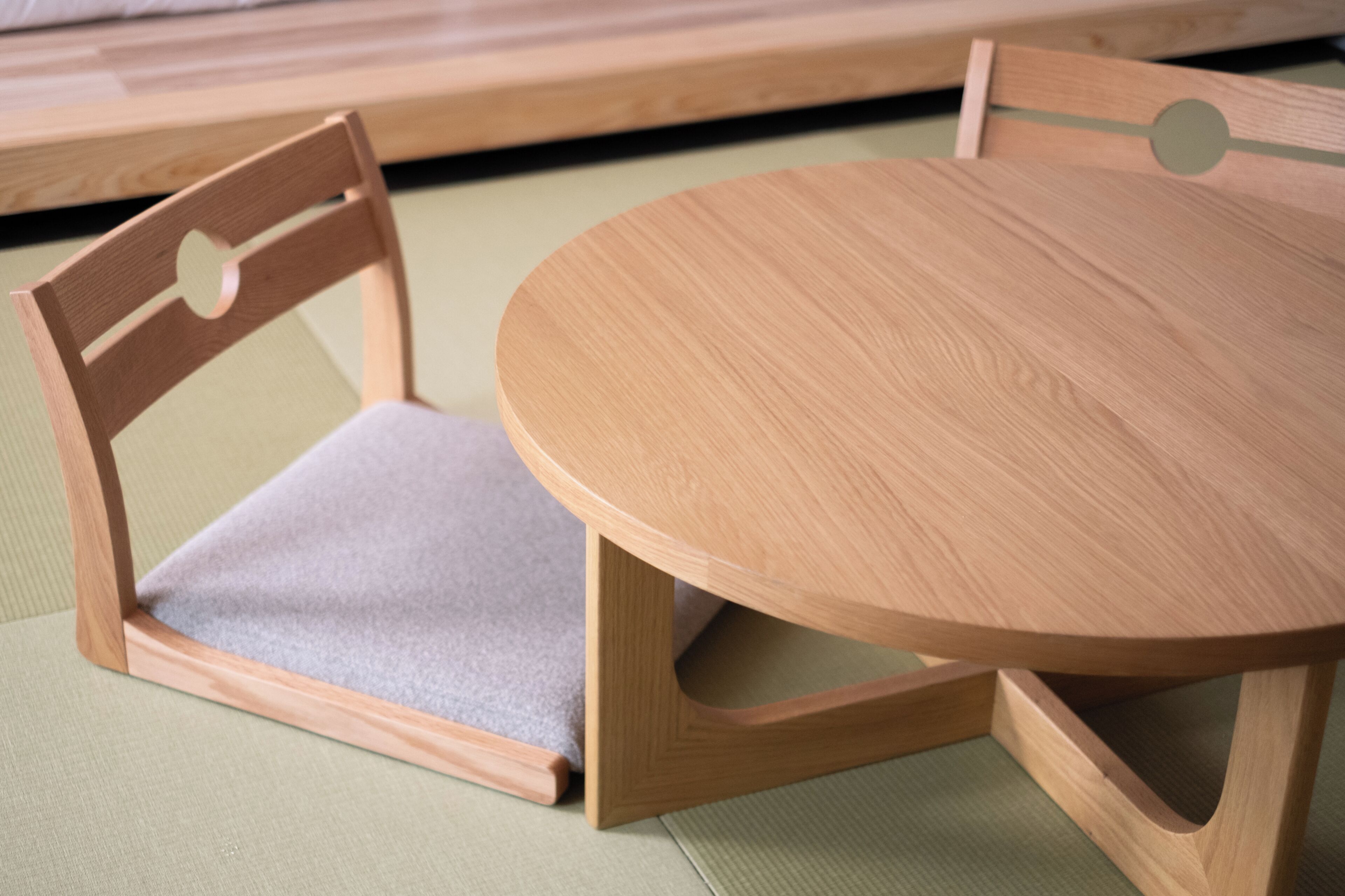 A wooden dining table with a round shape and a chair with a cushioned seat.