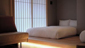 Una camera da letto moderna con un letto, una poltrona e una finestra con persiane verticali.