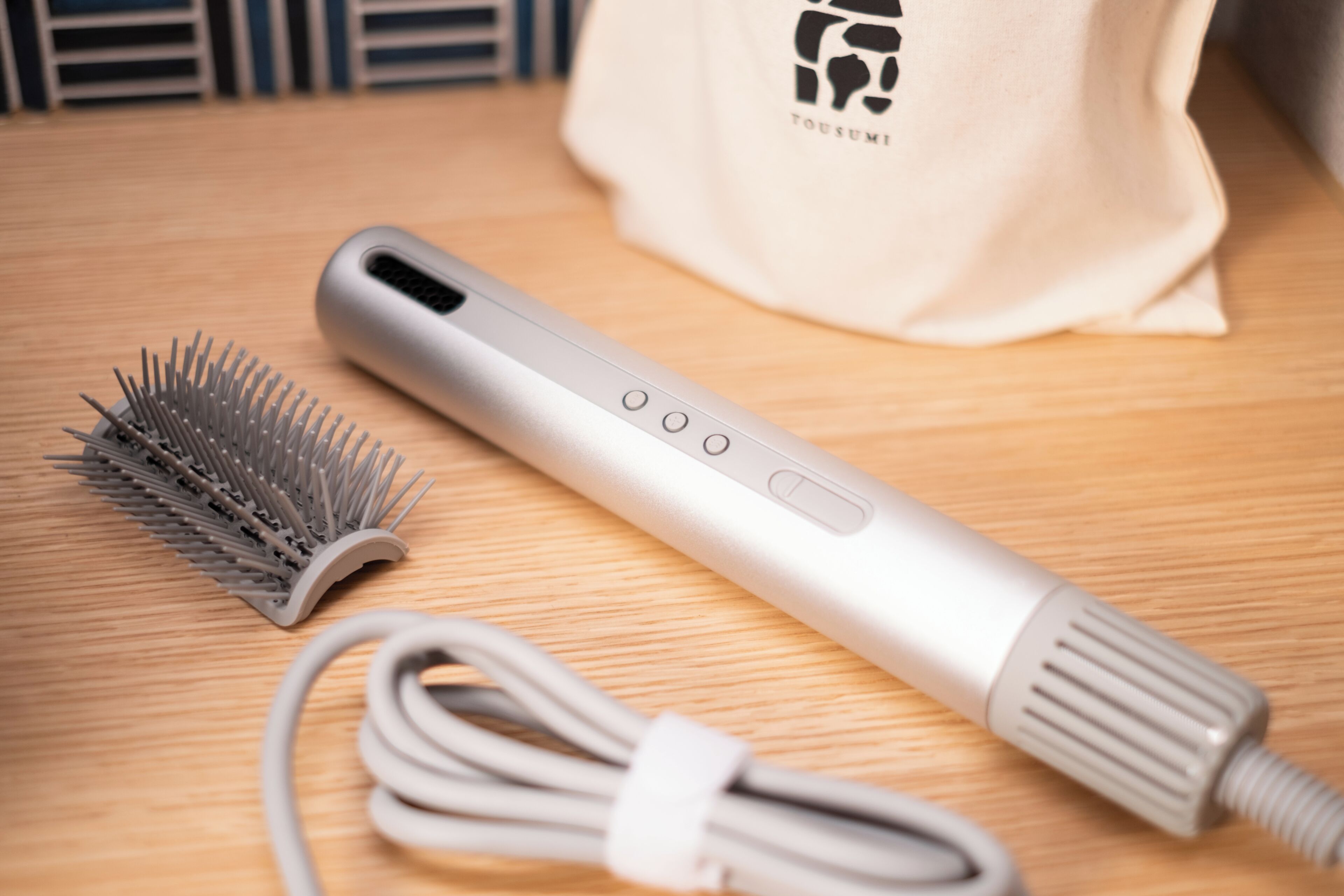 Un utensilio para peinar cabello con cable y cepillo sobre una superficie de madera.