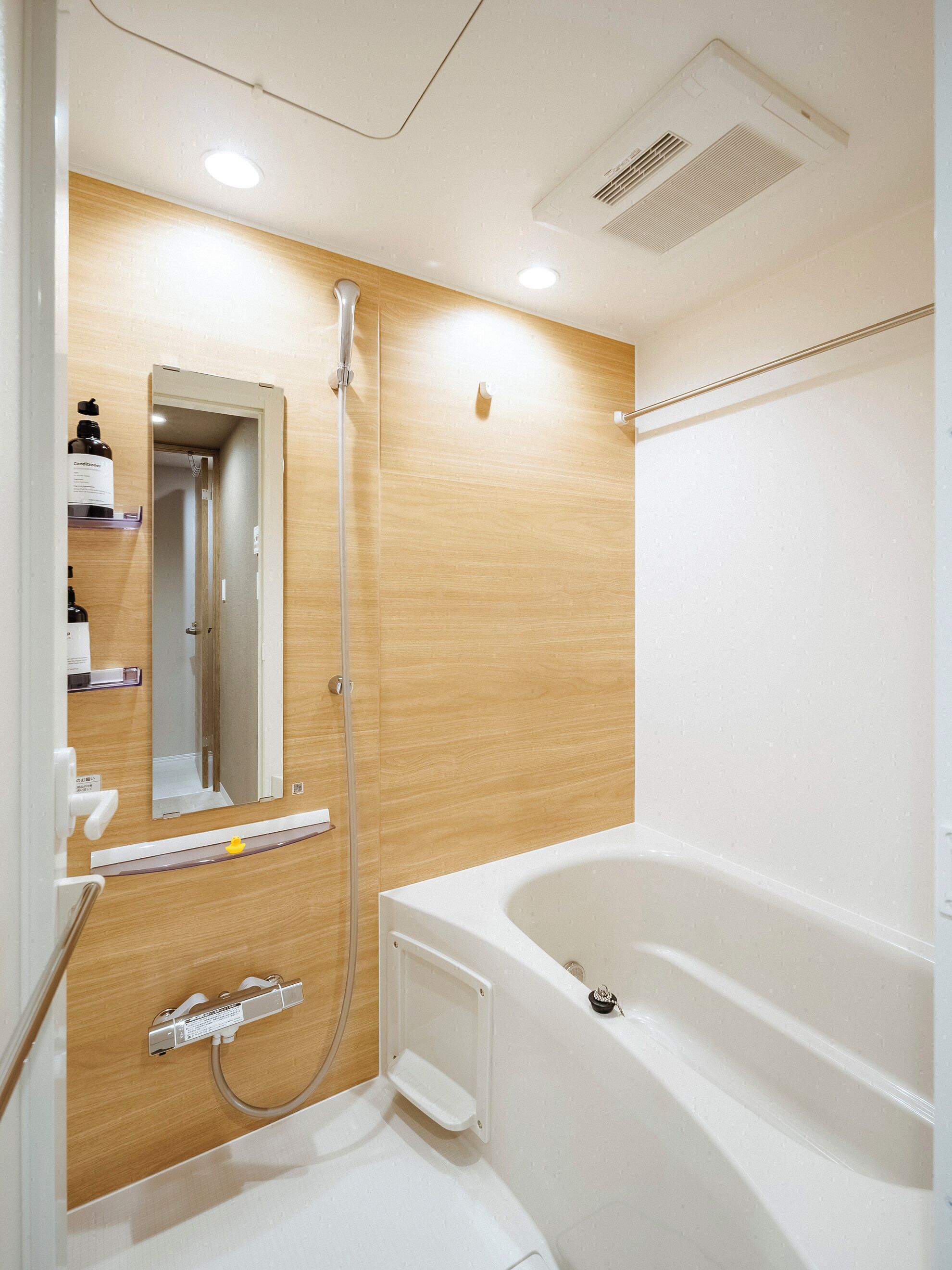 Un baño moderno con tocador de madera, un espejo grande, una bañera y una ducha.