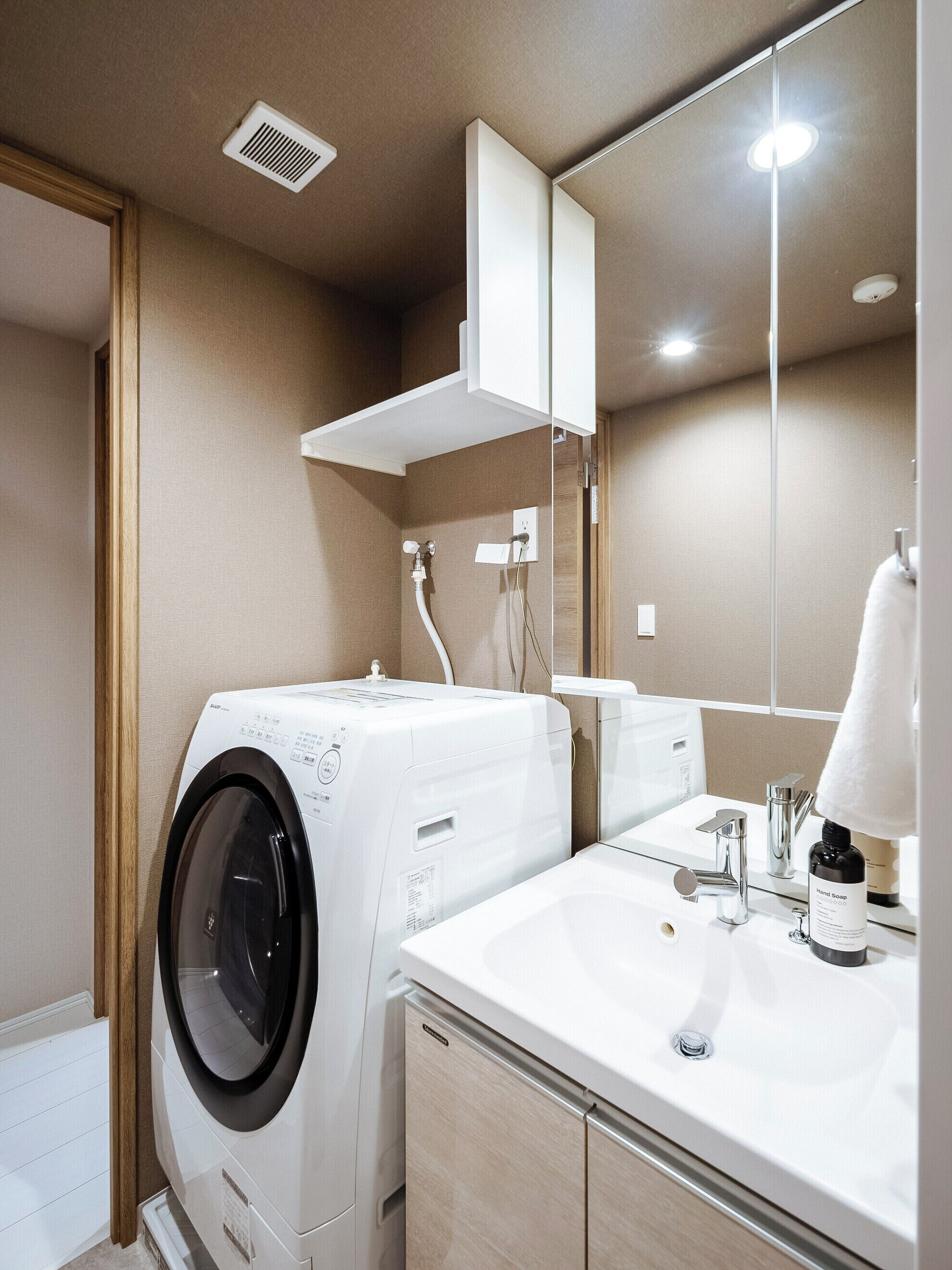 A modern bathroom with a washing machine, a sink, and a mirror.