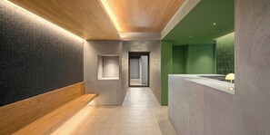 A modern interior with a wooden bench, a reception desk, and a green accent wall.