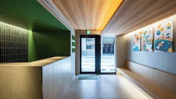 A modern interior with a reception desk, a wooden ceiling, and colorful artwork on the walls.
