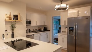 Een moderne keuken met witte kasten, een roestvrijstalen koelkast en een inbouwfornuis.