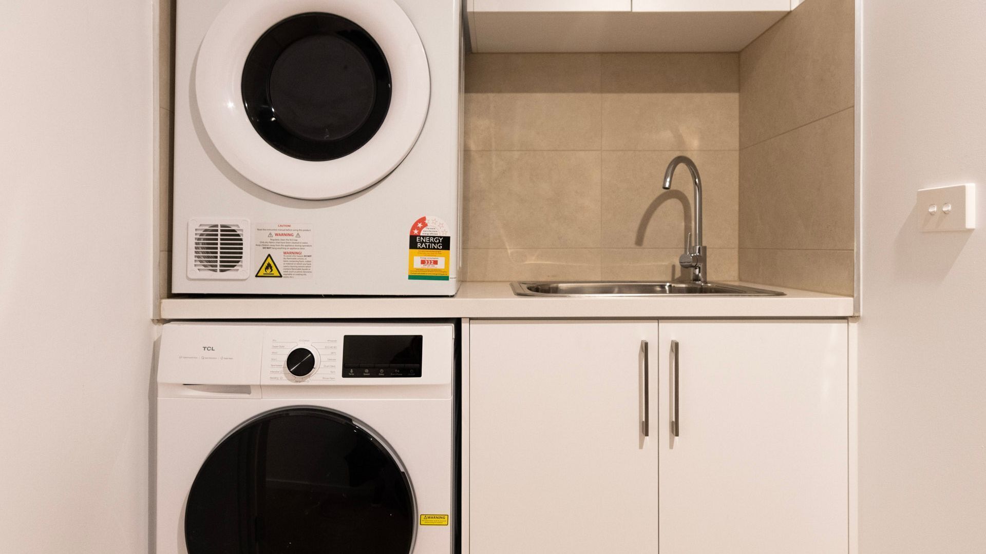 A compact laundry area with a washing machine, dryer, and sink.