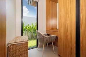 A corner room with a view of greenery, a wicker basket, and a chair.