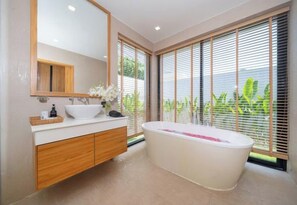 Une salle de bain moderne avec une baignoire sur pieds, un grand miroir et un meuble-lavabo en bois.