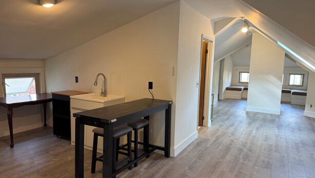 Un loft espacioso con zona de cocina, una mesa de comedor y una escalera que lleva a una zona de estar en altura.