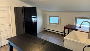 Una cocina con un refrigerador negro, una ventana y un lavamanos.