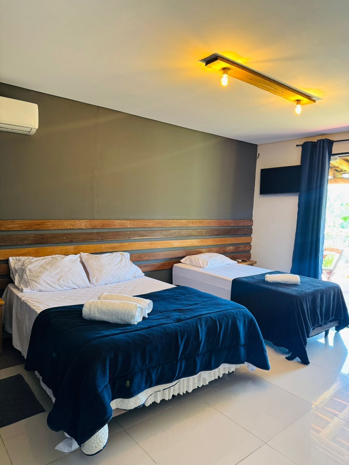 A hotel room with two beds, a flat-screen TV, and a ceiling light fixture.