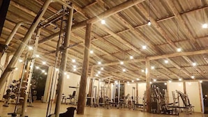 Ein geräumiges Fitnessstudio mit verschiedenen Trainingsgeräten, hohen Decken und freiliegenden Balken.