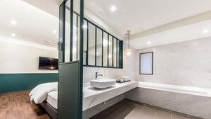 A modern bathroom with a large bathtub, a vanity with a sink, and a large mirror.