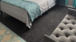 Et hotelværelse med to senge, en sofa, en lænestol, et skrivebord og et billede på væggen.