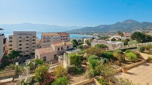Une ville côtière avec des bâtiments, un port de plaisance et des montagnes en arrière-plan.