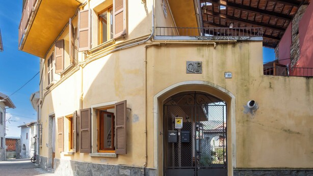 A building with a yellow facade, an arched entrance, and a metal gate. - La Giuseppina by Interhome (Brovello Carpugnino)