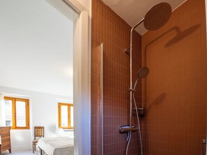 Une salle de bain avec une douche, un lit et une fenêtre.