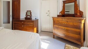 A bedroom with a bed, wooden dresser, and a mirror. - La Giuseppina by Interhome (Brovello Carpugnino)