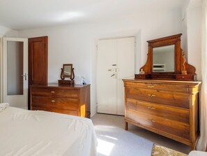 A bedroom with a bed, wooden dresser, and a mirror. - La Giuseppina by Interhome (Brovello Carpugnino)