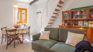 A cozy living room with a green sofa, wooden cabinet, and a dining area with a table and chairs. - La Giuseppina by Interhome (Brovello Carpugnino)