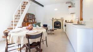 A modern kitchen with a fireplace, a dining area with a table set for four, and a staircase leading to an upper level. - La Giuseppina by Interhome (Brovello Carpugnino)