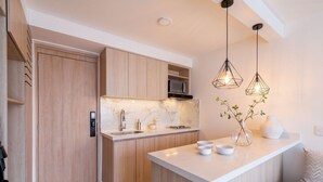 A modern kitchen with wooden cabinets, a marble countertop, a built-in microwave, and pendant lighting. - Edificio Miro Guadalupe (Cali)